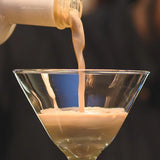 Liquid being poured from a bottle into a glass against a dark background