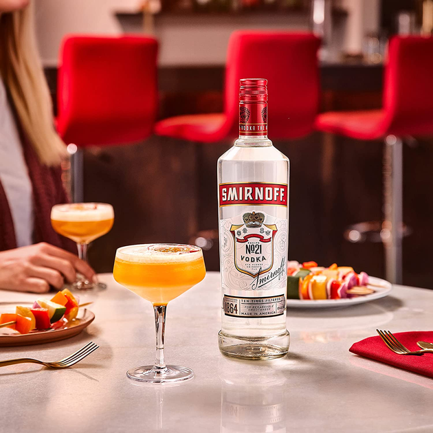 Smirnoff bottle on a table with cocktails and snacks in a restaurant setting