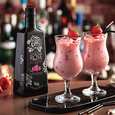 Bottle of Tequila Rose with two strawberry milkshakes on a bar counter