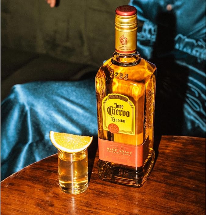 Jose Cuervo bottle with a shot glass and lime wedge on a wooden surface