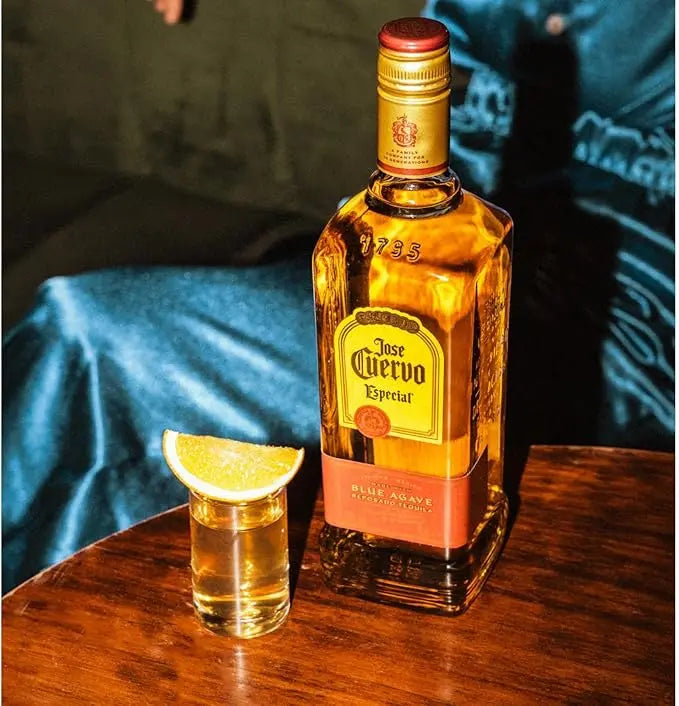 Jose Cuervo bottle with a shot glass and lime wedge on a wooden surface