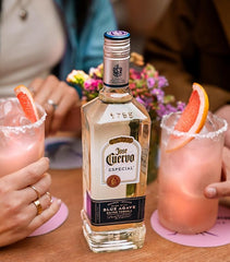 Bottle of Jose Cuervo tequila with two cocktails on a table