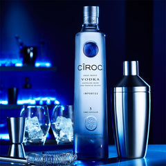 Ciroc vodka bottle with cocktail shaker and glasses on a dark background