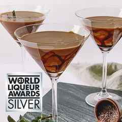 Three martini glasses with a chocolate liqueur cocktail on a gray surface, with 'World Liqueur Awards Silver' logo.