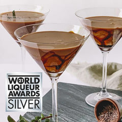 Three martini glasses with a chocolate liqueur cocktail on a gray surface, with 'World Liqueur Awards Silver' logo.