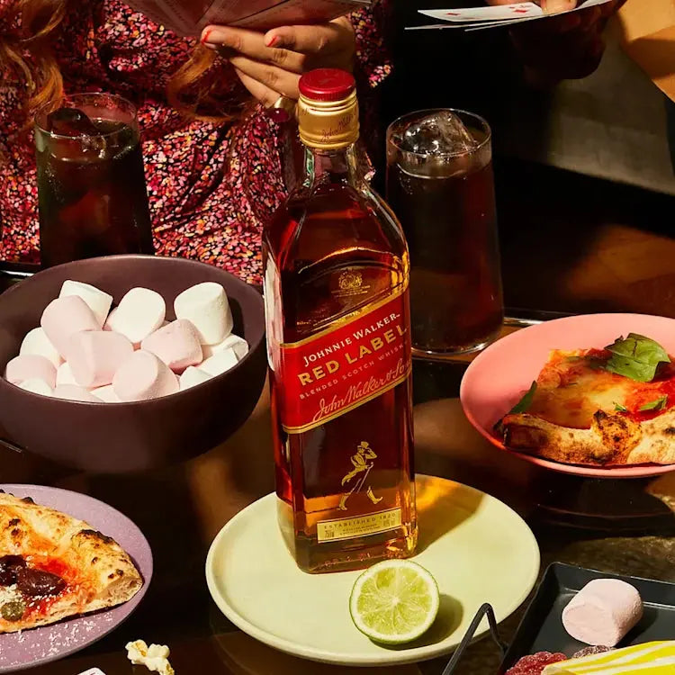 Johnnie Walker Red Label whisky bottle on a table with food and drinks