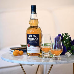 Glen Moray whisky bottle with two glasses on a marble table.