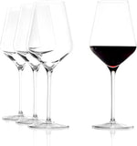 Set of wine glasses with one filled with red wine on a white background