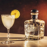 Don Julio tequila bottle with a cocktail garnished with a lime wheel on a wooden surface.