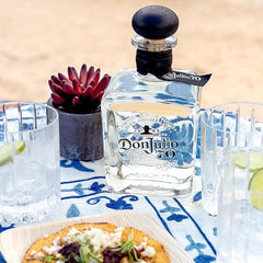 Don Julio 70 tequila bottle on a table with food and glasses