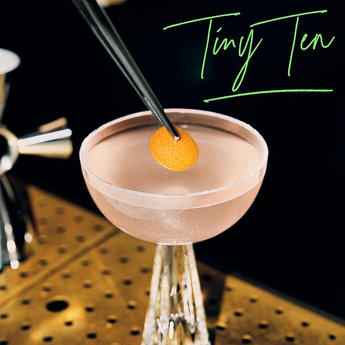 Cocktail in a pink glass with a lemon twist on a black background, featuring 'Tiny Tea' text.