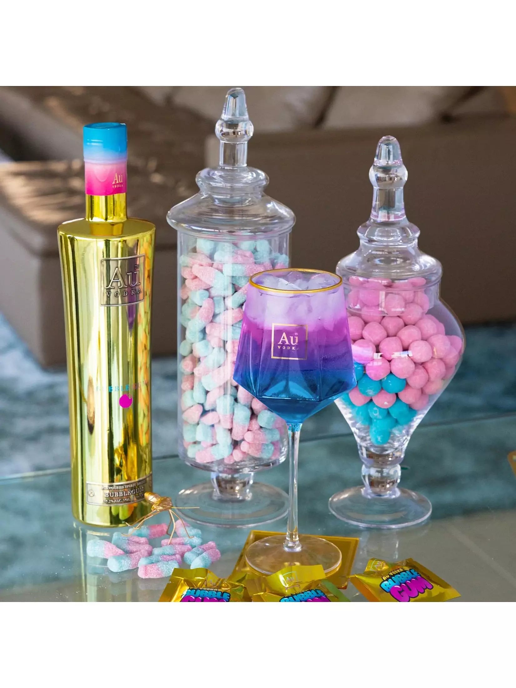 Colorful bottle, wine glass, and candy jars on a table with a blurred background