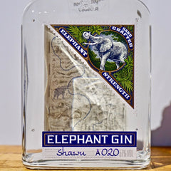 Bottle of Elephant Gin with a label featuring an elephant design on a wooden surface.
