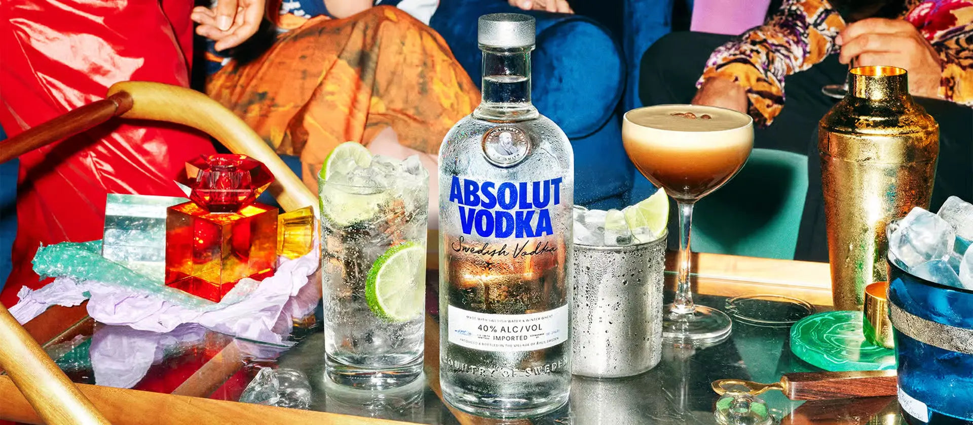 Absolut Vodka bottle with cocktails and bar accessories on a table