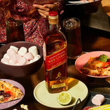 Johnnie Walker Red Label whisky bottle on a table with food and drinks